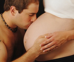 husband kissing his pregnant wife belly